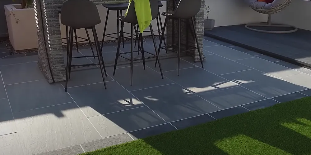 Carrelage posé dans un jardin avec chaise de jardin, table et gazon synthétique