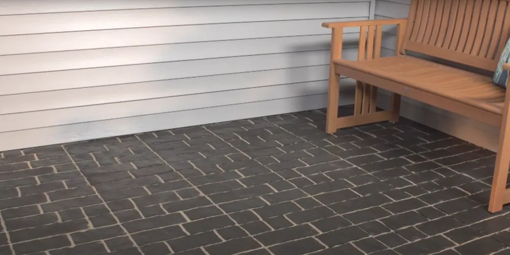 A patio featuring interlocking paving stones, with a garden bench placed on the surface